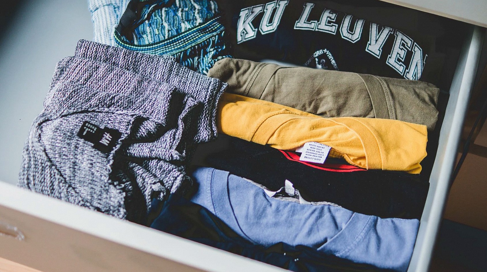 引き出しに整然と並べられた服やTシャツ、カジュアルウェアの展示。